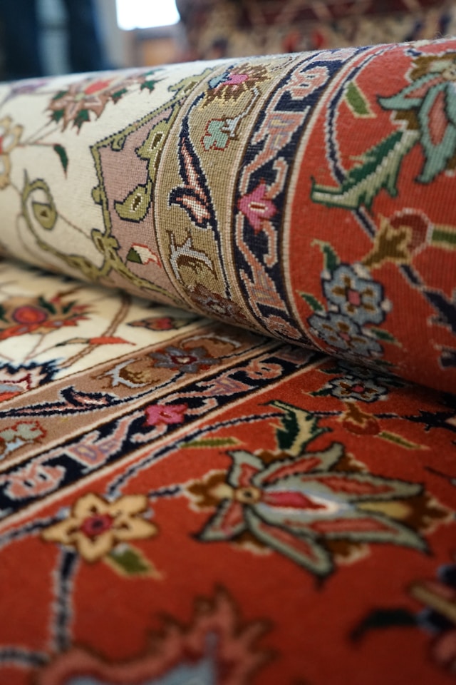 Close-up of rolled Persian-style rugs in red, cream, and floral patterns