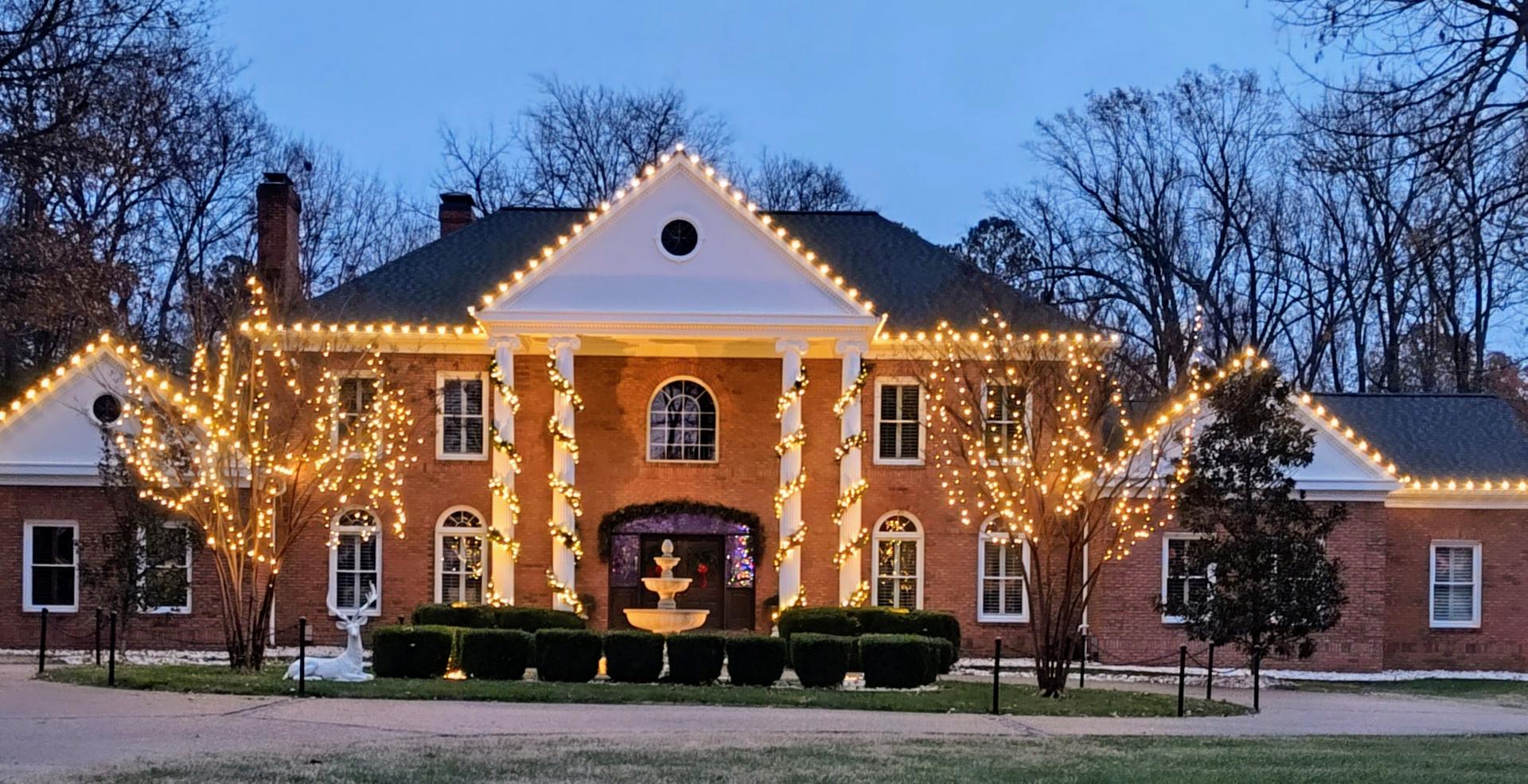 a house with warm white christmas lights, warm white garland and trees canopy wrapped in Paducah KY
