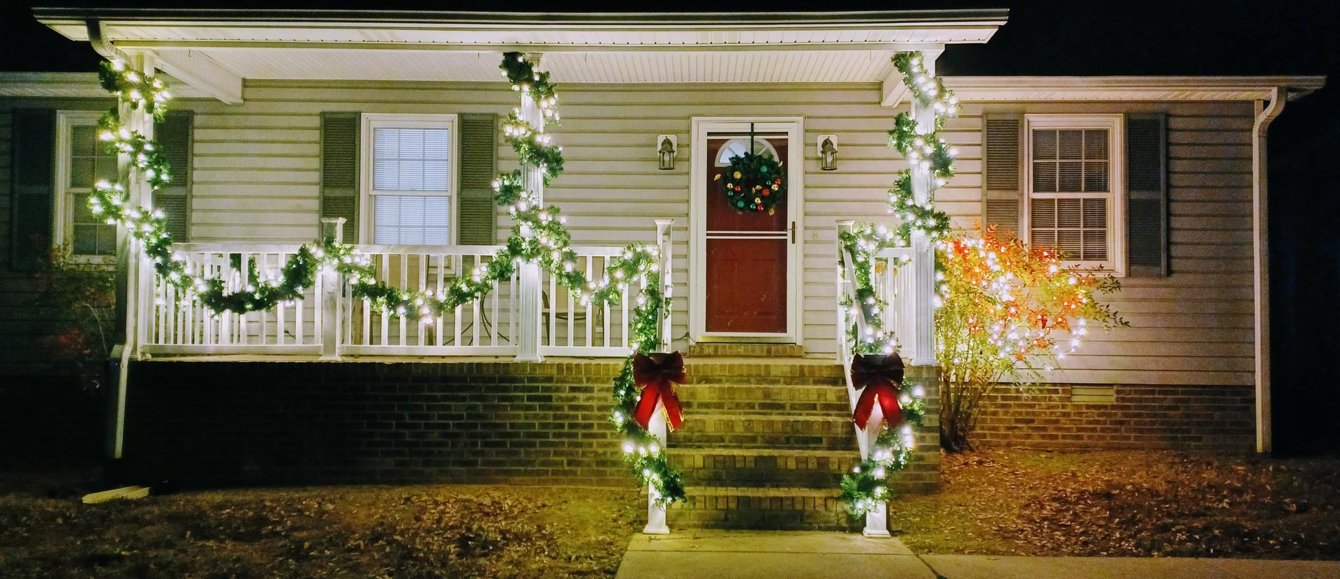 a house with warm white pre lit garland and red bows 