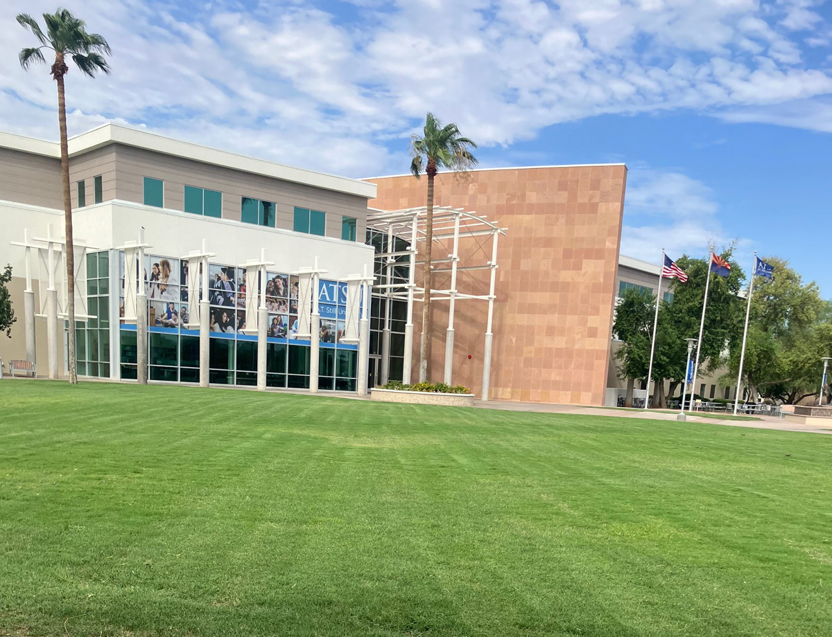 Commercial office building with a manicured lawn, palm trees, and flagpoles out front Commercial office building with a manicured lawn, palm trees, and flagpoles out front