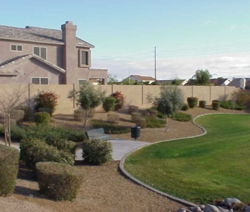 HOA common area with mown lawn, a curving walkway, and rock beds behind two-story homes HOA common area with mown lawn, a curving walkway, and rock beds behind two-story homes