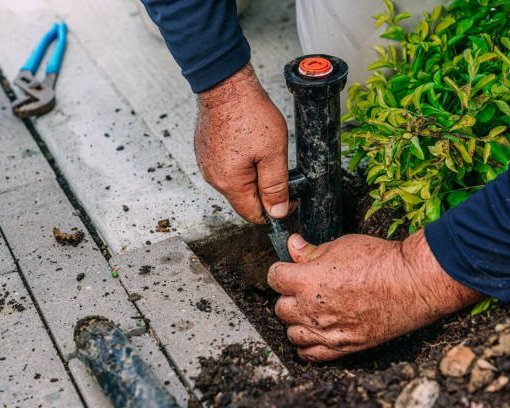 Technician adjusting a sprinkler head while troubleshooting an irrigation system