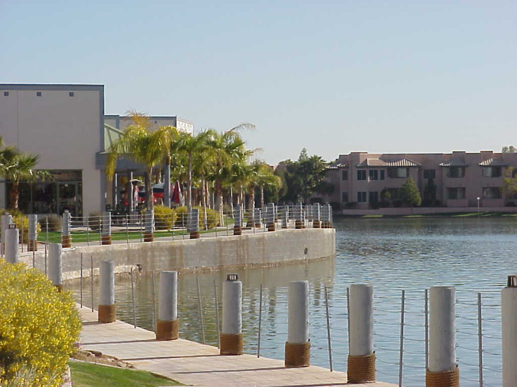 Waterfront walkway with bollard lights and palms along an apartment community lake Waterfront walkway with bollard lights and palms along an apartment community lake