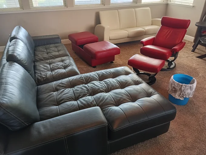 Living room with a black leather sectional sofa, red leather recliner and ottoman, and a cream sofa in the background