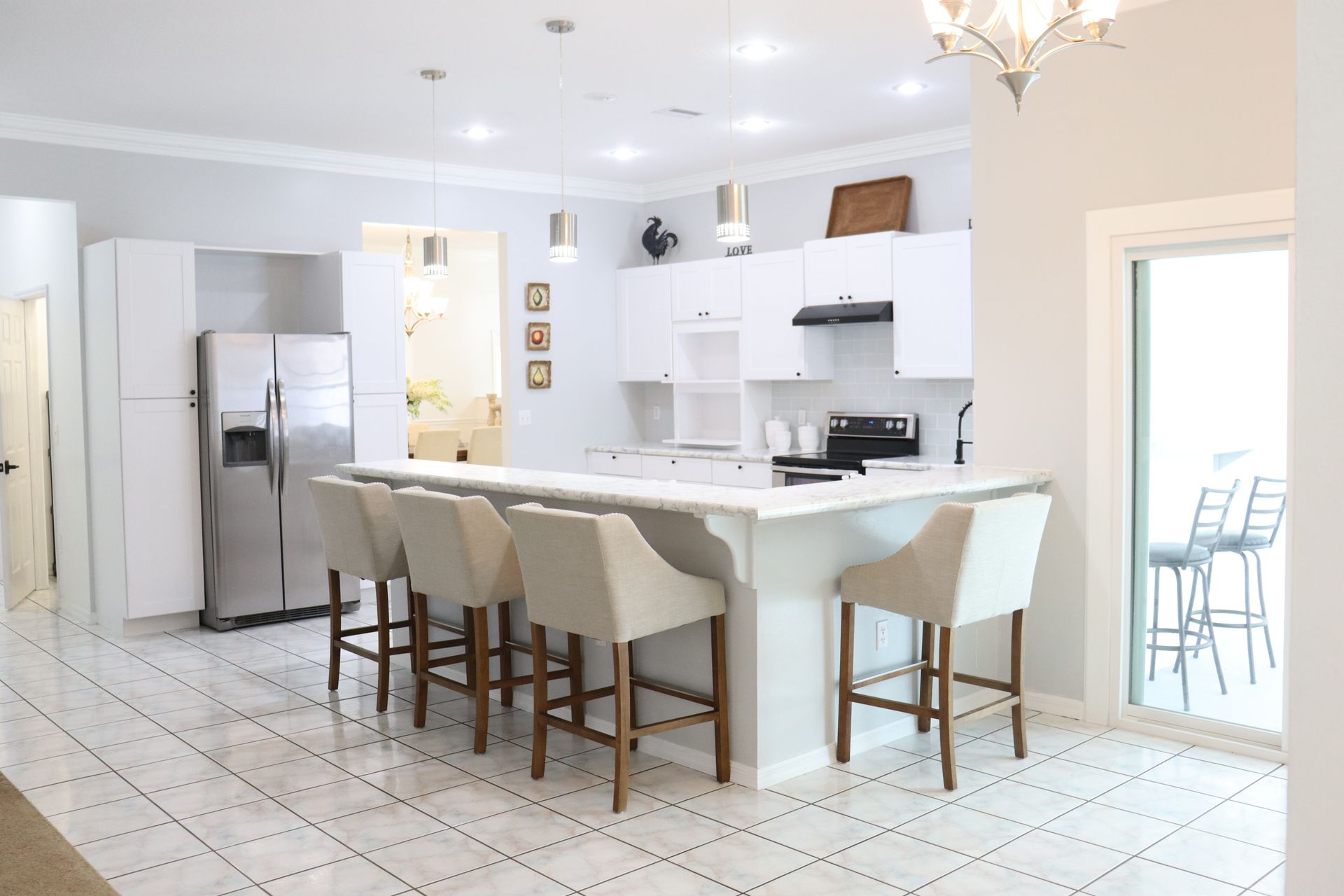 Kitchen with white tile flooring, white cabinetry, and a bar-height island Kitchen with white tile flooring, white cabinetry, and a bar-height island