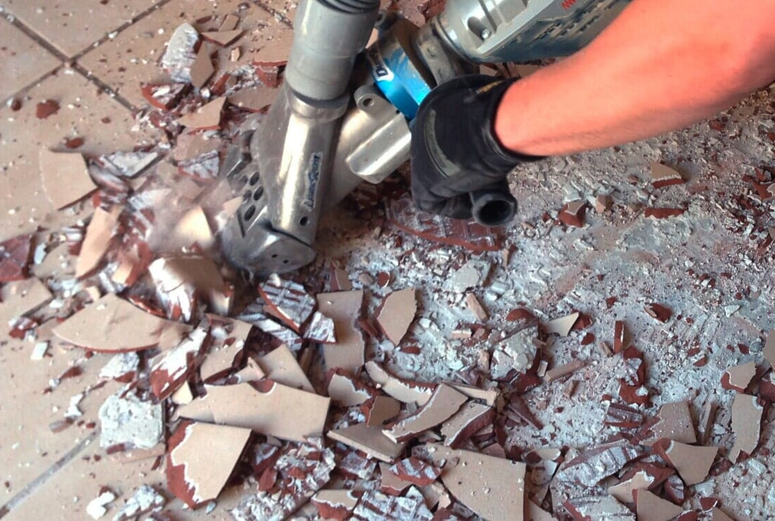 a person using a machine to remove tile flooring a person using a machine to remove tile flooring