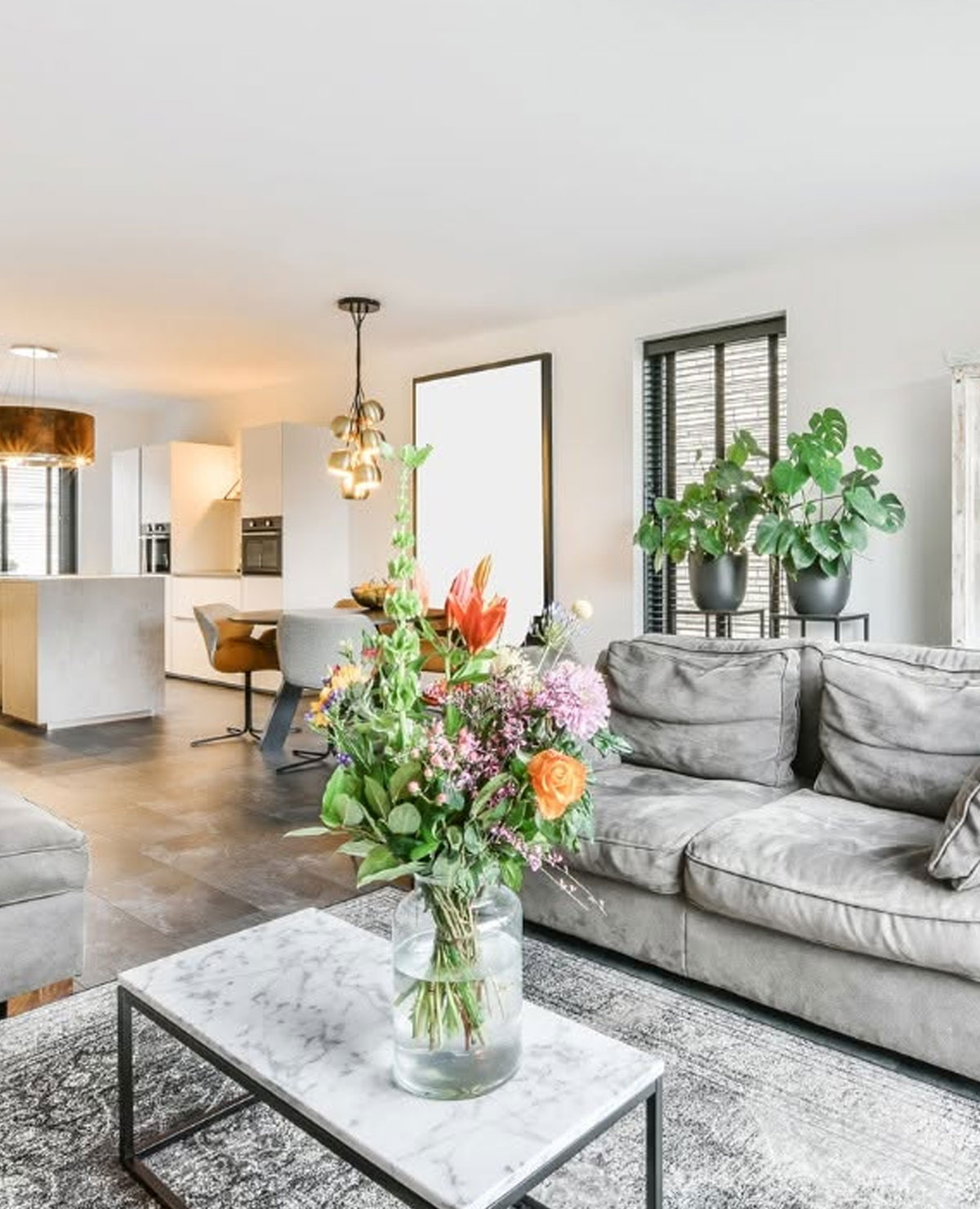 a living room with a couch and a vase of flowers a living room with a couch and a vase of flowers