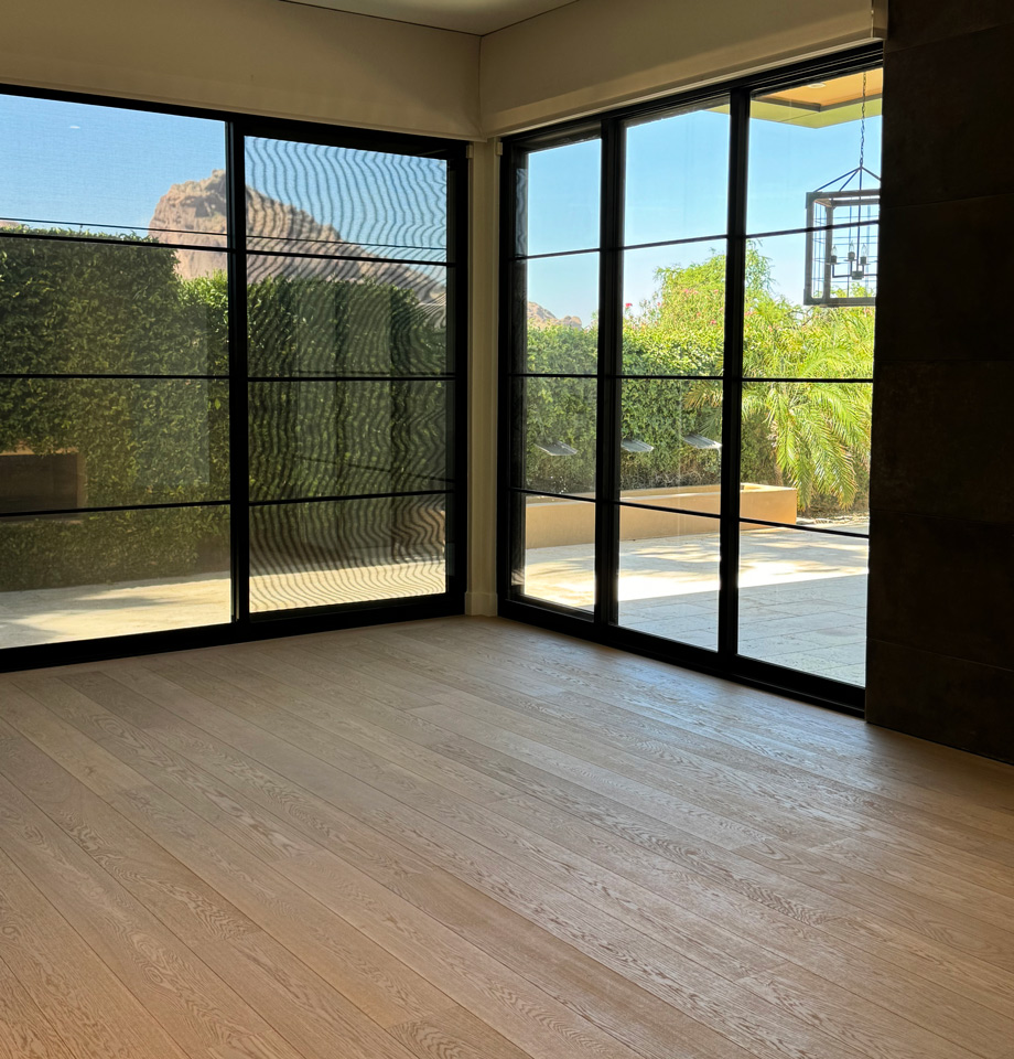 Modern living room with wide-plank oak flooring, a stone fireplace wall, and a mountain view window Modern living room with wide-plank oak flooring, a stone fireplace wall, and a mountain view window