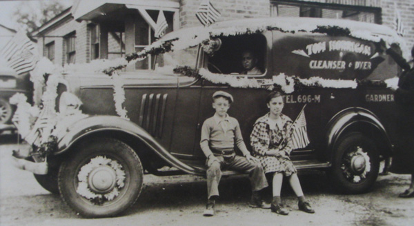 Vintage Horrigan Cleaners delivery truck decorated with flags, with two children on the bumper Vintage Horrigan Cleaners delivery truck decorated with flags, with two children on the bumper