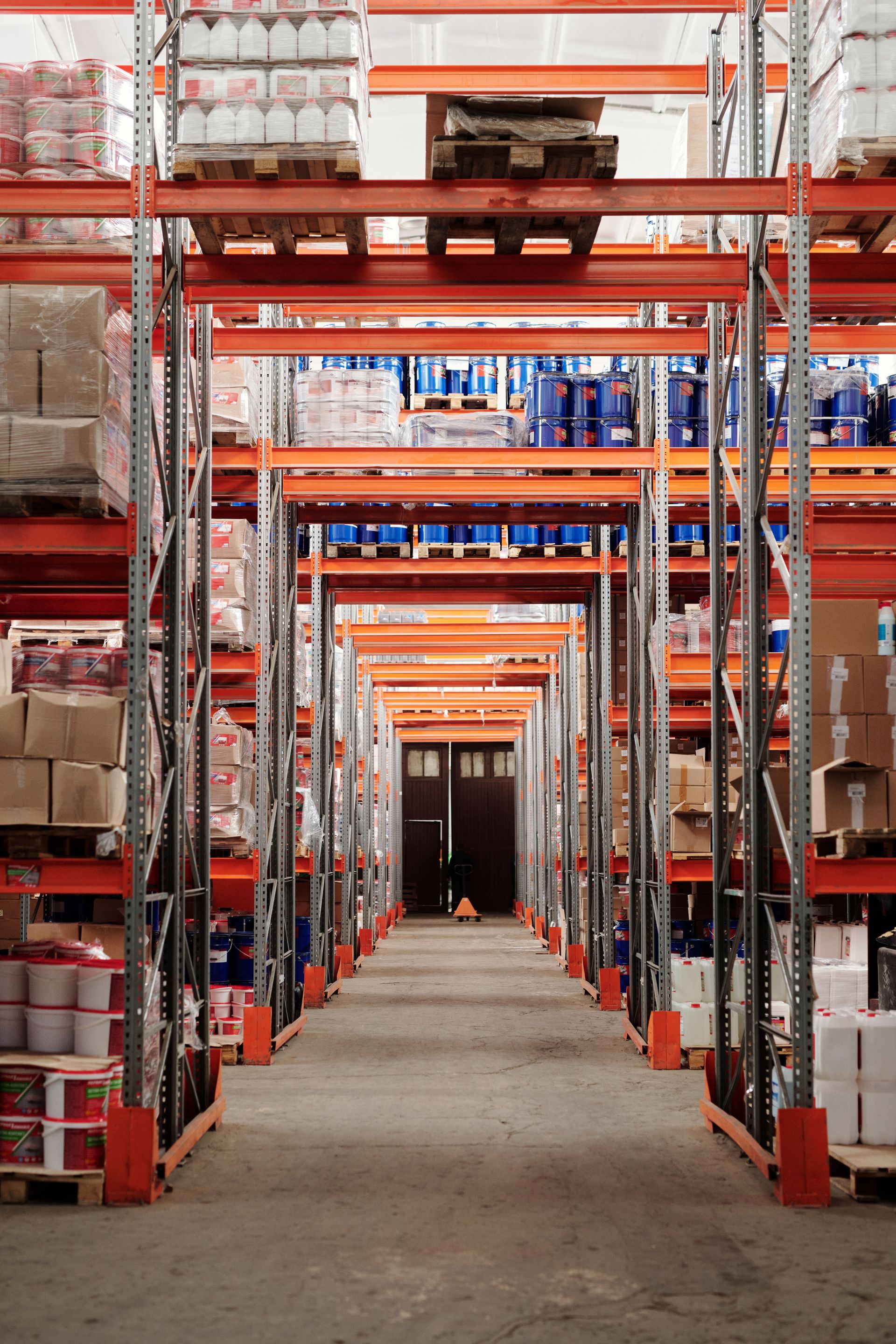 Warehouse aisle lined with orange pallet racking and stacked boxes on a sealed floor
