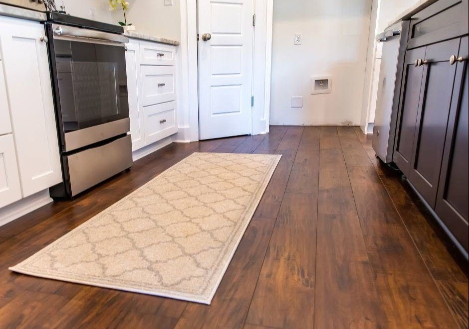 Cream patterned runner rug on dark hardwood between white kitchen cabinets and a stainless range Cream patterned runner rug on dark hardwood between white kitchen cabinets and a stainless range