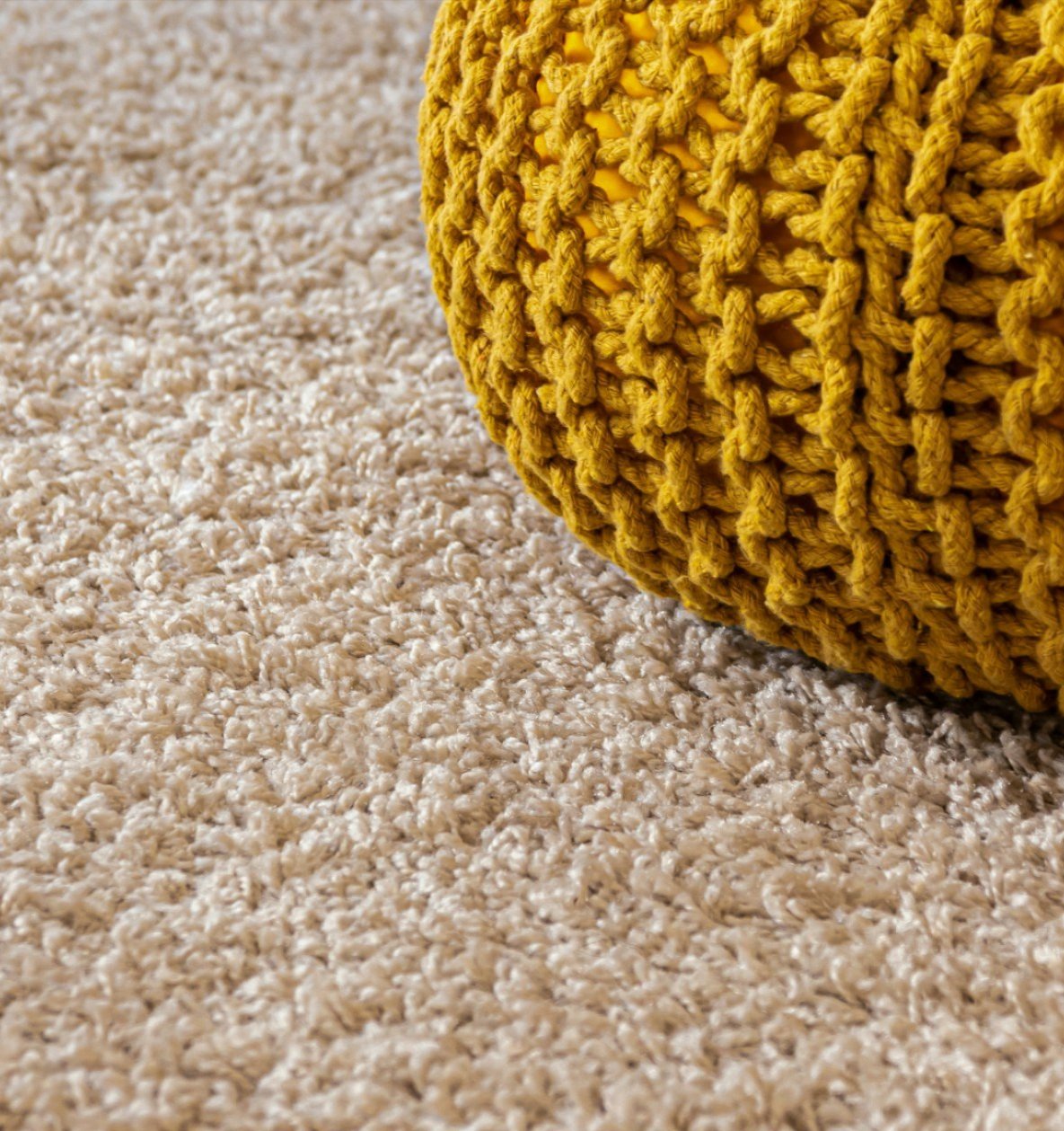 Yellow knit pouf resting on deep-pile cream carpet cleaned to a soft, even finish
