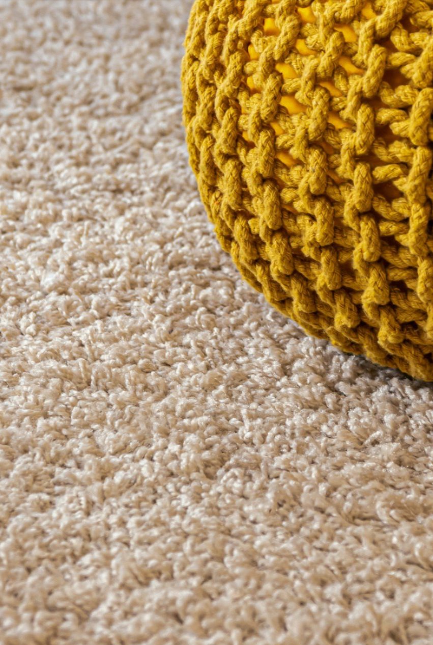 Yellow knit pouf resting on deep-pile cream carpet cleaned to a soft, even finish Yellow knit pouf resting on deep-pile cream carpet cleaned to a soft, even finish