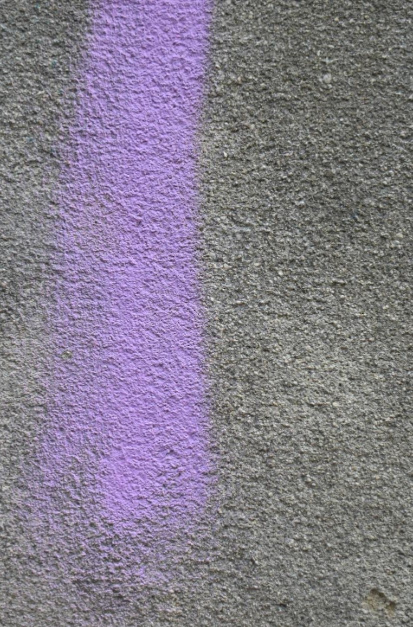 UV blacklight revealing a hidden pet stain glowing purple across grey wall-to-wall carpet