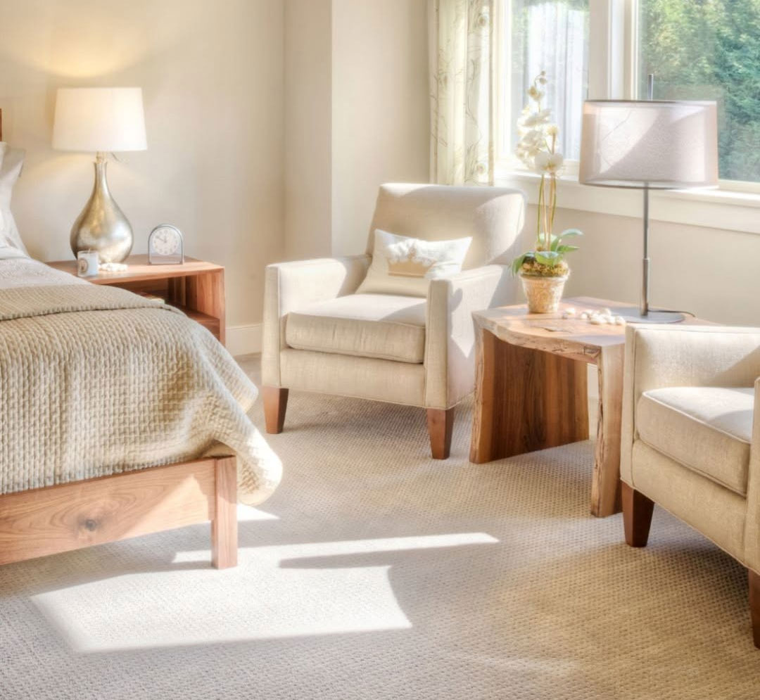 Sunlit bedroom with cream upholstered armchairs and freshly cleaned pale wall-to-wall carpet